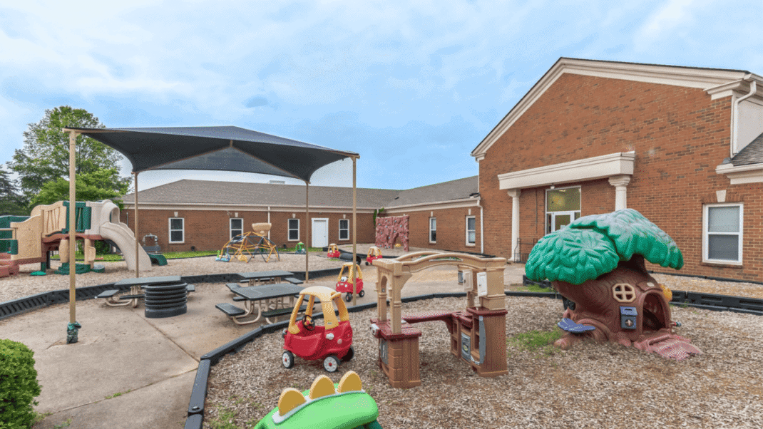 Outdoor playground with playhouse, slide, and sandbox for children.